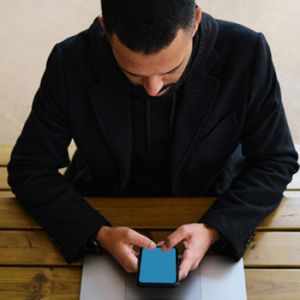 Hombre frente a su Laptop con su celular revisando proceso de creación de marca digital