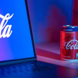 Una lata de Coca Cola junto a una laptop con una imagen de un logo de la marca que representa revolución de marketing de marca
