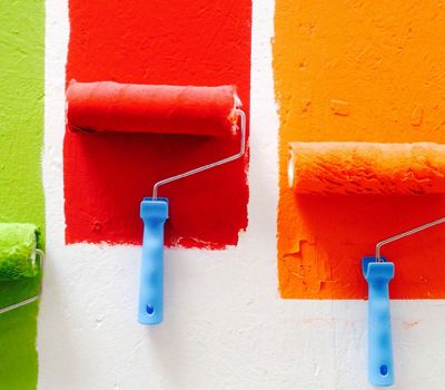 Rodillos con colores diferentes trazando una línea de color en una pared