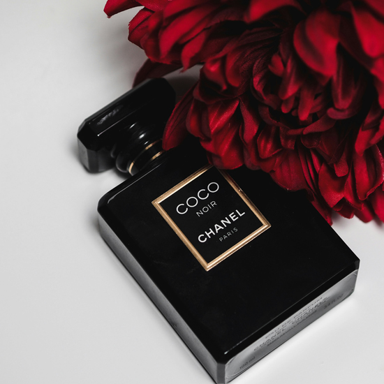 Frasco de perfume junto a una rosa roja