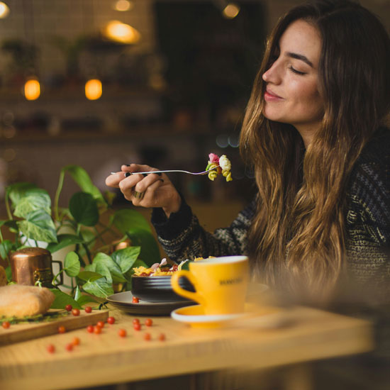 Mujer sentada en mesa comiendo mostrando satisfacción y lealtad del cliente gracias al branding