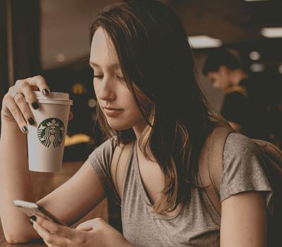 Mujer con taza de café de starbucks mostrando el branding y la responsabilidad social