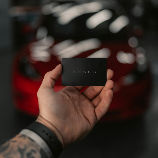 Detalle de persona sosteniendo tarjeta con marca Tesla mostrando la estrategia de implementación de branding visual