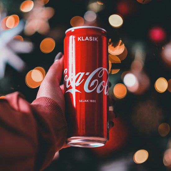 Coca Cola en mano con fondo navideño mostrando experiencias memorables con el branding emocional