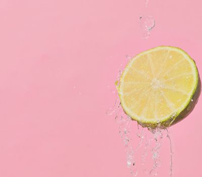 Limón y agua sobre fondo rosado conceptualizando el cambio de logotipo a identidad de marca gracias al branding