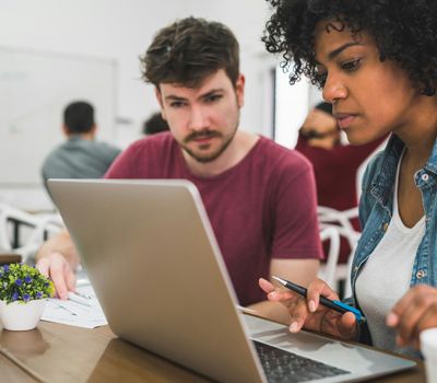 Hombre y mujer frente a computador trabajando en estrategias de comunicación de marca para empresas con Unonu Agencia