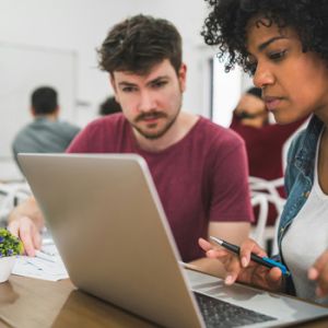 Hombre y mujer frente a computador trabajando en estrategias de comunicación de marca para empresas con Unonu Agencia