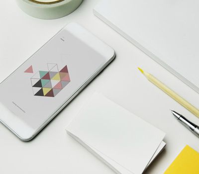 Diferentes elementos sobre mesa y un celular con elementos gráficos alusivos al branding visual para el crecimiento empresarial