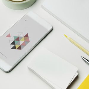 Diferentes elementos sobre mesa y un celular con elementos gráficos alusivos al branding visual para el crecimiento empresarial
