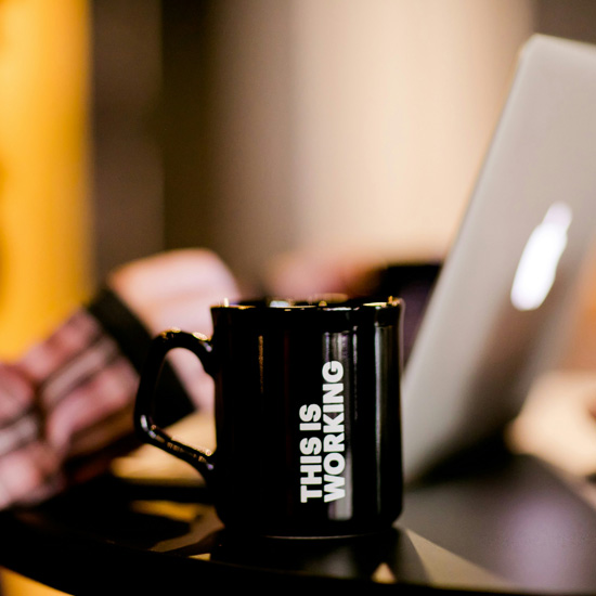 Experta de Unonu con mug y frase que dice estamos trabajando mostrando la eficiencia de la identidad de marca exitosa