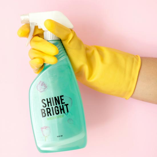 Plano cerrado de mano sosteniendo un producto de limpieza con etiqueta que muestra el refuerzo de marca en empresas de aseo con identidad gráfica creada por Unonu