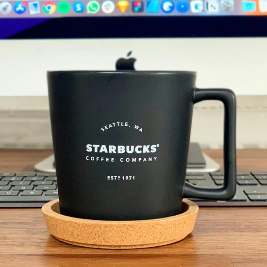 Plano cerrado de una taza de café personalizada con el fondo de un escritorio de un experto de Unonu que trabajó en un proyecto de branding exitoso
